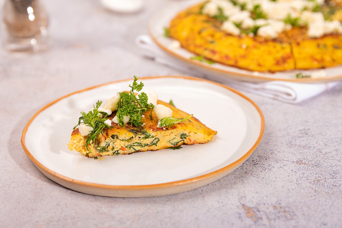 A piece of Veggie Frittata is laid on the plate. There is a plate of frittata to the right | Hurry The Food Up