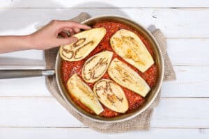 Woman's hand is placing aubergine slices into the pan | Hurry The Food Up