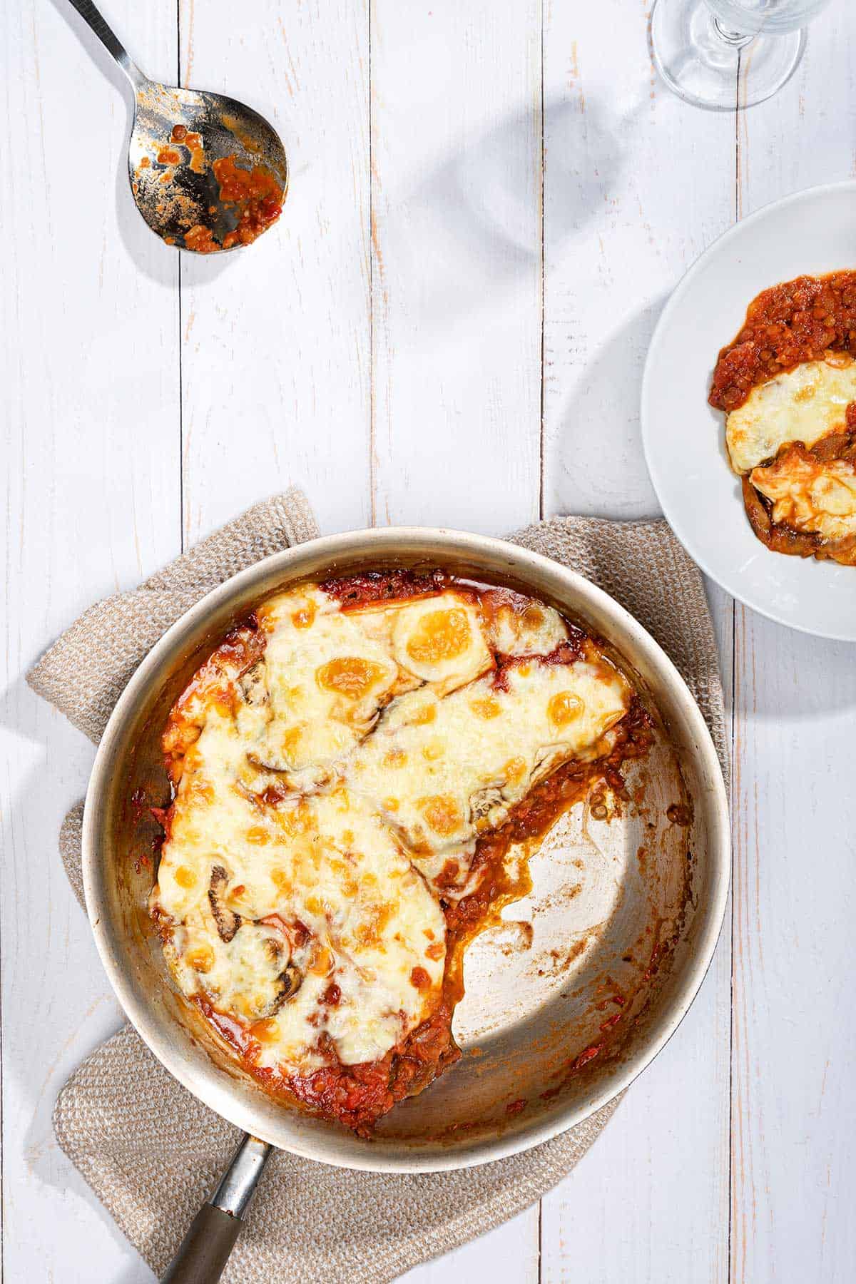 Vegetarian Moussaka is in ready in a pan and served on a plate with a tablespoon beside it | Hurry The Food Up